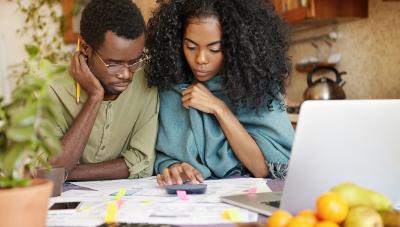 Photo of two people looking at financial papers with a calculator. 