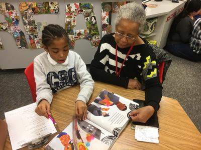 A student and a family member read a book in the library