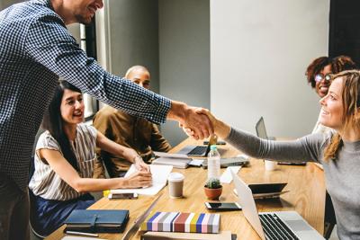 Man and woman shaking hands across a table.