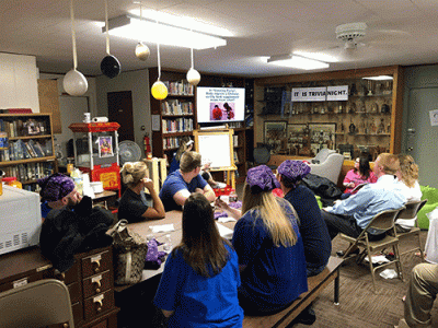 A group of trivia night participants looking at a question on a TV screen