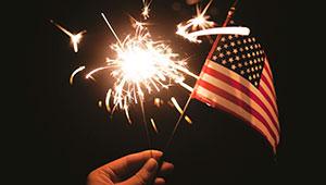 hand holding sparkler and US flag