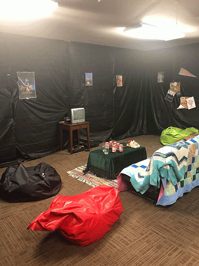 A couch in a room with a television and posters on the walls