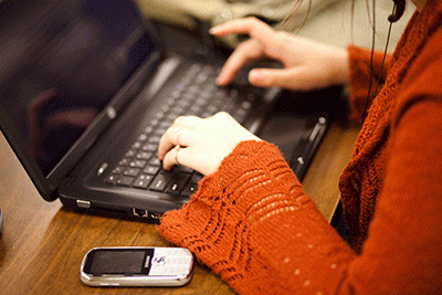 Close-up of hands typing on laptop