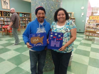 Two people holding patches from a story quilt