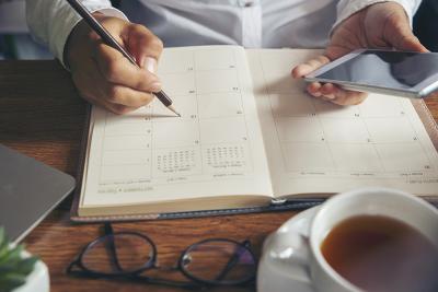 Photo of a person writing in a planner.