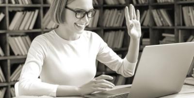 Woman on laptop smiling and waving to screen