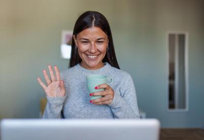 A woman holding a coffee cup looking at a computer screen